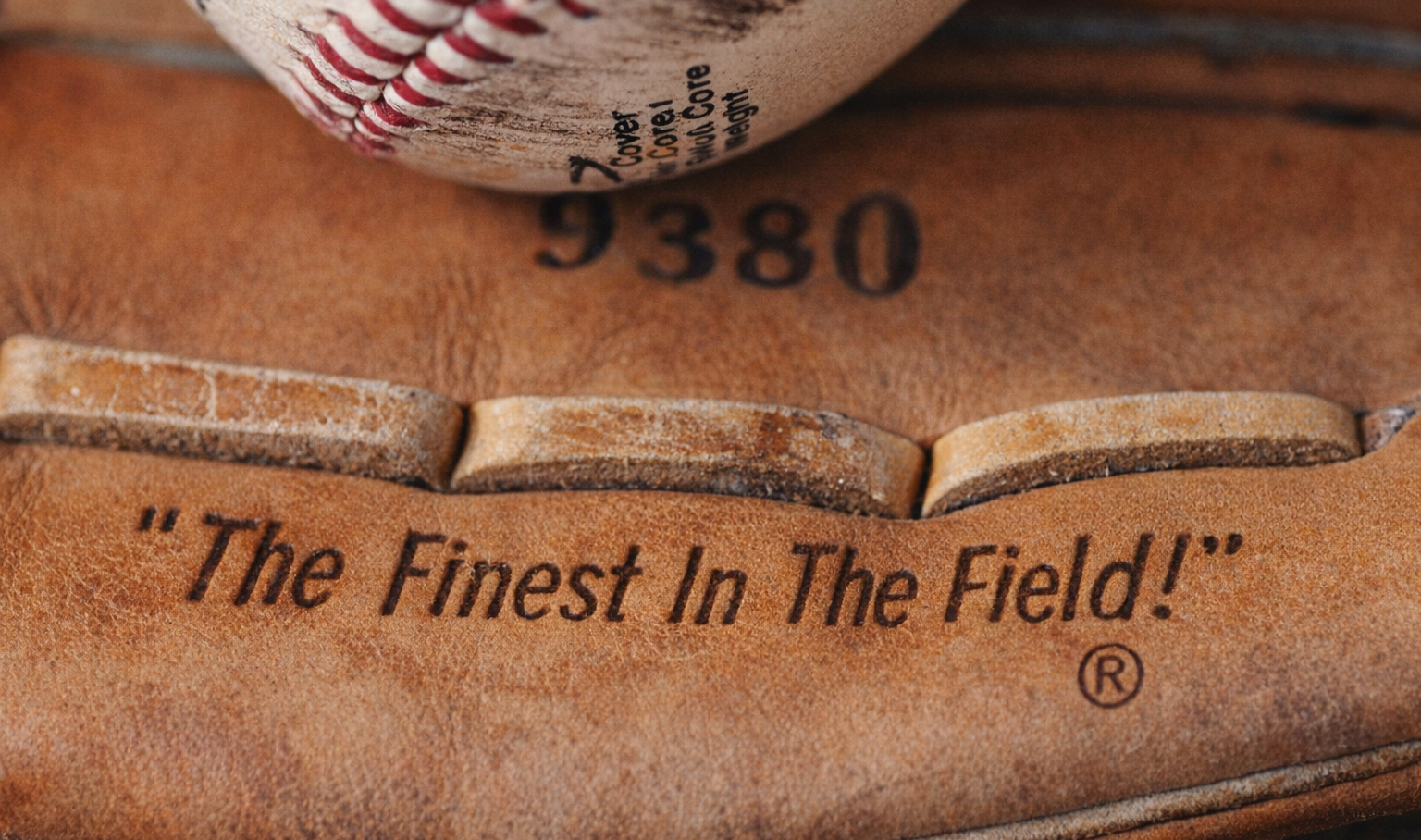 Baseball glove with 'The Finest In The Field!' inscription and a baseball on top.